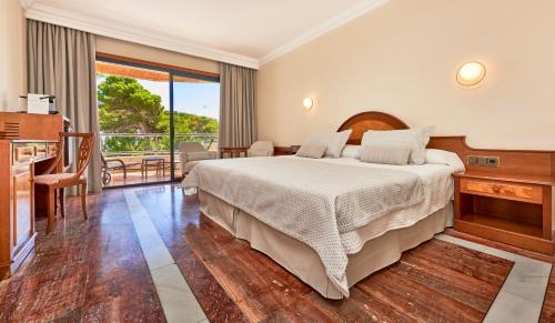a bedroom with a large bed and a balcony at Hotel Serrano Palace in Cala Ratjada