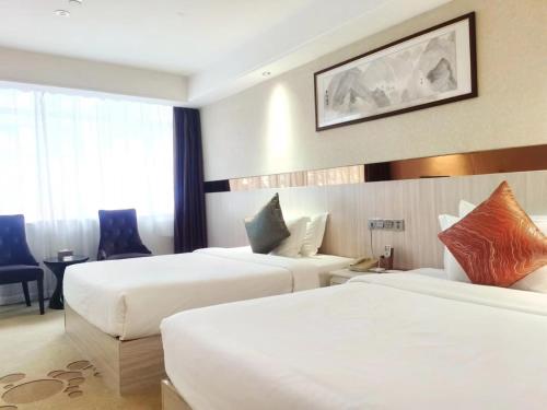 una camera d'albergo con 2 letti e una scrivania di Paco Hotel Tianhe Coach Terminal Metro Guangzhou a Canton