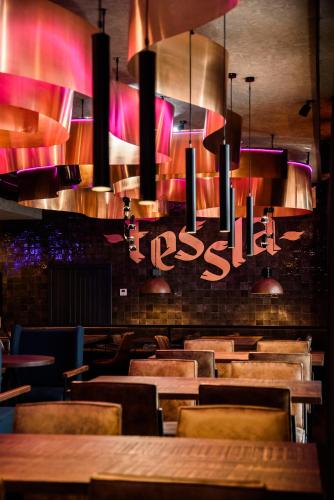 a restaurant with wooden tables and chairs and lights at Hotel Fessla in Kostanay