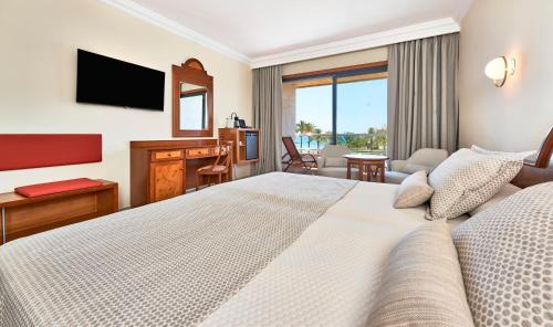 Cette chambre comprend un grand lit et un bureau. dans l'établissement Hotel Serrano Palace, à Cala Ratjada