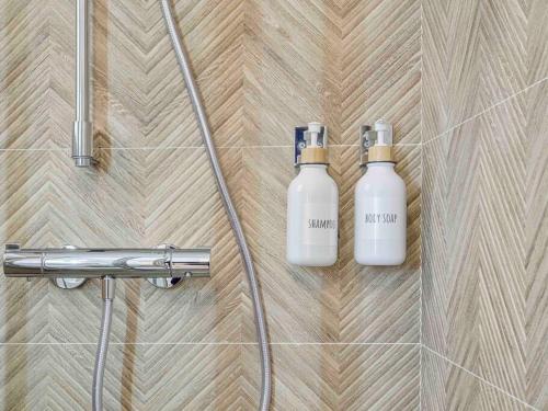 Duas garrafas de dorizers estão sentadas na parede da casa de banho em Casa Mandarina: 4 Bedrooms - 2 Terraces - Parking em L'Hospitalet de Llobregat