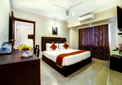 sypialnia z łóżkiem i biurkiem z misą owoców w obiekcie Chirag Inn w mieście Thiruvananthapuram