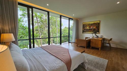 a bedroom with a bed and a desk and windows at Maxwell Villa Bali in Tabanan