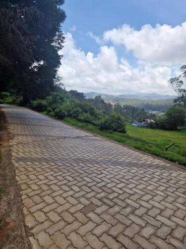 a cobblestone road with trees on the side at Narmada Holiday Home in Ooty