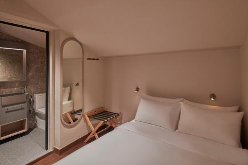 a bedroom with a large white bed and a bathroom at KINN Studios in Singapore