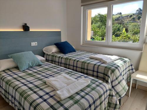 2 Betten in einem Zimmer mit 2 Fenstern in der Unterkunft Apartamentos La Tata in Avilés