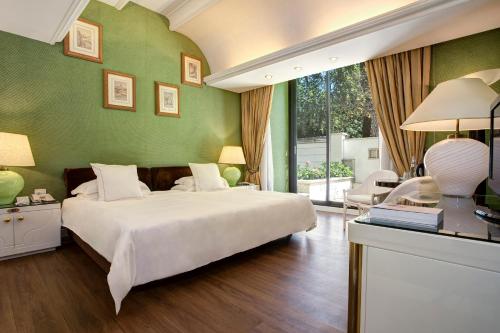 1 dormitorio con cama blanca y pared verde en Hotel Lord Byron - Small Luxury Hotels of the World en Roma