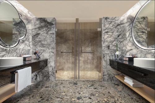 a bathroom with a shower and two sinks at Hotel Indigo Guangzhou Haixinsha by IHG - Free Shuttle Bus to Canton Fair Complex during Canton Fair period in Guangzhou