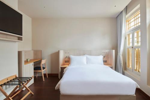 a bedroom with a large white bed and a desk at KINN Studios in Singapore