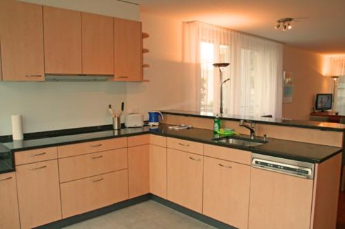 a kitchen with wooden cabinets and a black counter top at Nest - Feldhof 5 in Zug