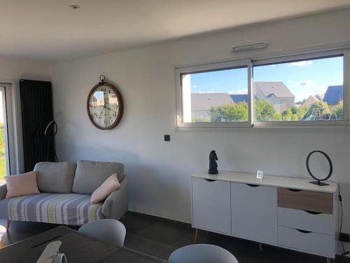 un salon avec un canapé et une horloge au mur dans l'établissement Location saisonnière Maen Roch, à Les Portes du Coglais