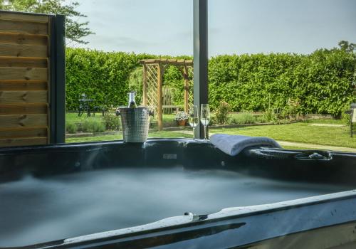 a bath tub with a view of a garden at The Apple Shed Norfolk in Horsford