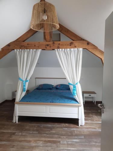 1 dormitorio con cama con dosel y sábanas azules en Le moulin de la Chaîrâ 