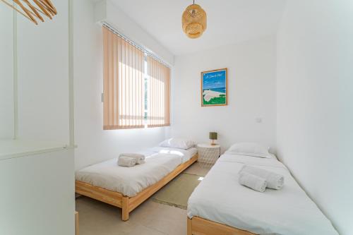 Duas camas num quarto com paredes brancas e uma janela em Nathaniel - Appt terrasse 5 min de la plage em Arcachon