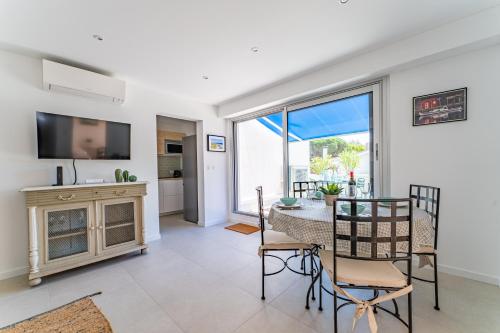 un salon avec une table, des chaises et une télévision dans l'établissement Nathaniel - Appt terrasse 5 min de la plage, à Arcachon