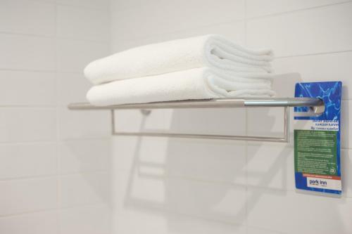 a towel rack with towels and a box on it at Park Inn by Radisson Hotel Astana in Astana