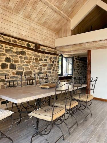 Cette chambre est dotée d'une table, de chaises et d'un mur en pierre. dans l'établissement Domaine des Combes - La Ferme aux Anes 14 pers., à Millau