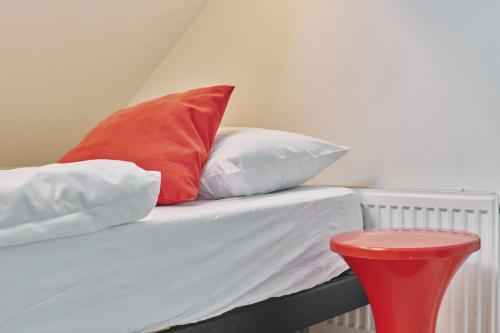 a bed with four pillows and a red stool at The Legacy by 2GO4 City Center in Brussels