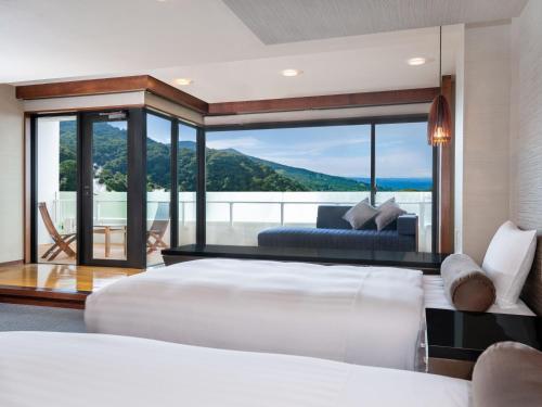 a bedroom with a large white bed and a couch at Kirishima Kokusai Hotel in Kirishima