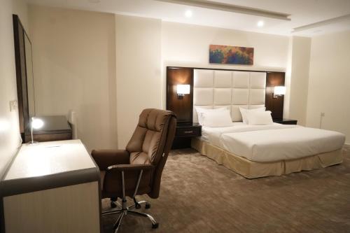 艾卜哈的住宿－فندق رحيب للشقق المخدومة Rahib Suites，酒店客房配有一张床、一张桌子和一把椅子。