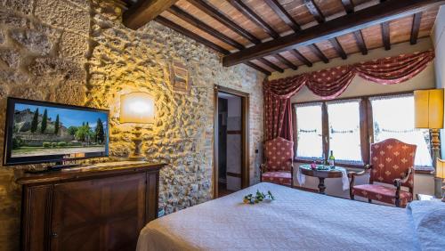 a bedroom with a bed and a tv in a room at Castel Pietraio WineResort in Monteriggioni
