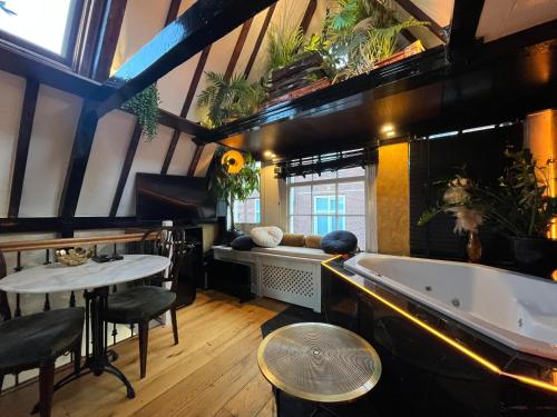 um quarto com uma banheira, uma mesa e cadeiras em The Enlightened House Luxury Suites em Amsterdã