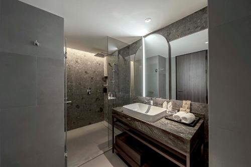 a bathroom with a sink and a shower at Gardina Asoke Hotel & Residence in Bangkok
