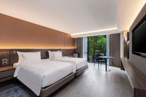 a bedroom with two beds and a flat screen tv at Gardina Asoke Hotel & Residence in Bangkok