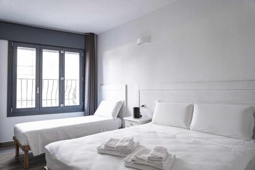 a white bedroom with two beds and a window at Domo Orise Alloggio in pieno centro in Orosei