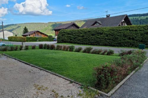 un giardino di erba verde con case sullo sfondo di Le Petit Bois a Les Rousses