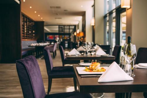a restaurant with tables and chairs with a plate of food at Radisson Blu Waterfront Hotel, Jersey in Saint Helier Jersey