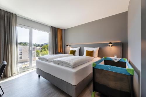 a bedroom with a bed and a tv and a window at Maxx Hotel Aalen in Aalen