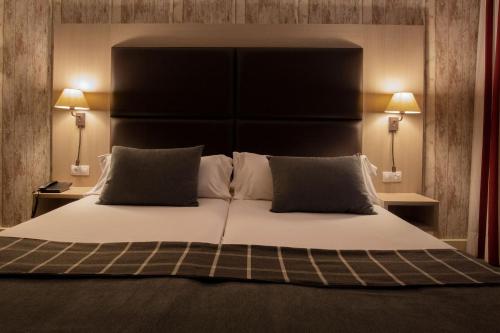 a large bed with a black headboard and two lamps at Hotel Himàlaia Soldeu by Nexta in Soldeu