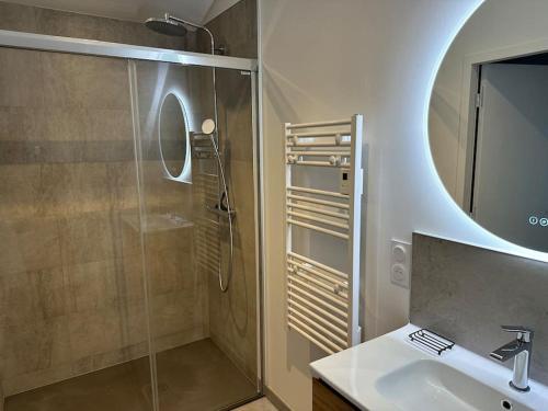 uma casa de banho com um chuveiro, um lavatório e um espelho. em Magnifique longère au calme em Trégunc