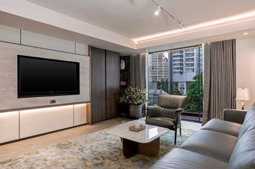 a living room with a couch and a tv at Gardina Asoke Hotel & Residence in Bangkok