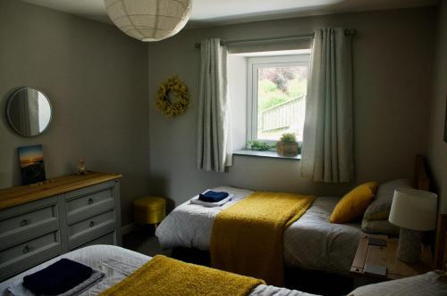 a bedroom with two beds and a window at Converted Stables at Peaceful Family Farm Stay in Pembrokeshire