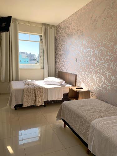 1 dormitorio con 2 camas y ventana en Hotel Ideal, en Chapecó
