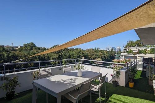 einen Balkon mit einem Tisch und Stühlen auf dem Dach in der Unterkunft Appart 7P vue Seine, Tour Eiffel in Issy-les-Moulineaux