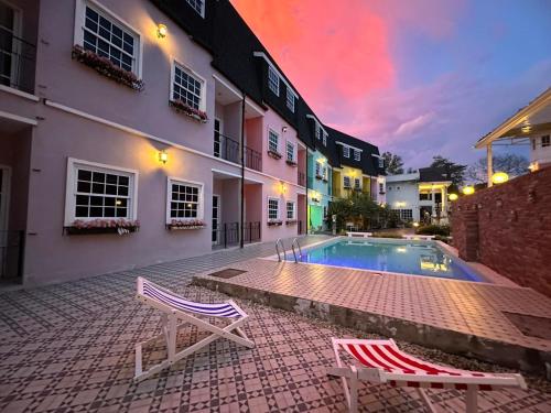 a house with a swimming pool and two chairs at ณ บ้านแม่ รีสอร์ท in Ban Rai