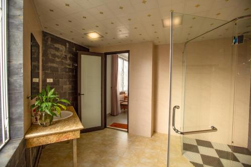 La salle de bains est pourvue d'une douche en verre et d'un lavabo. dans l'établissement Grand Flamant Hotel Sapa, à Sa Pa