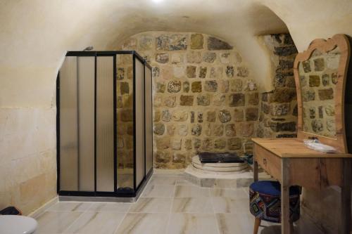 La salle de bains est pourvue de toilettes et d'un mur en pierre. dans l'établissement MİRSTONE TARİHİ KONAK, à Mardin