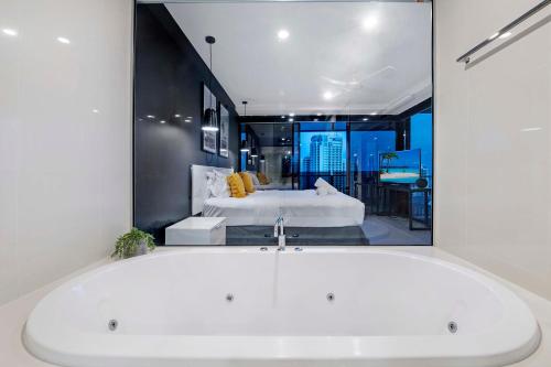 een badkamer met een bad en een grote spiegel bij Converted Two Bedroom Apartments at Circle on Cavill - Self Contained, Privately Managed in Gold Coast