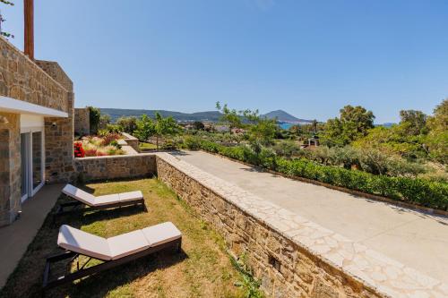 a patio with two white chairs and a stone wall at Luxury Villa Gialova Neokastro with Private Pool in Gialova