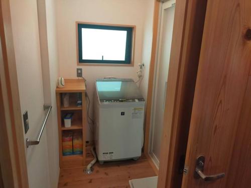 a small room with a refrigerator and a window at ファミリー向けの一棟貸切り別荘「セキデンファーム」 in Warao