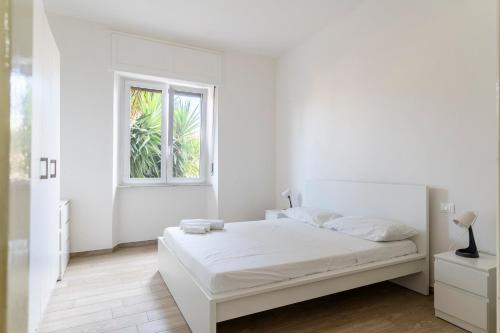 a white bedroom with a bed and a window at Livorno- Lungomare Viale Italia Bright Apartment! in Livorno