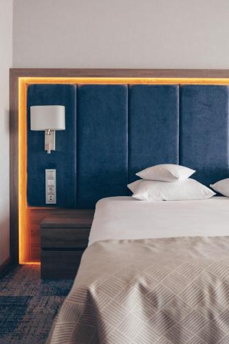 a bedroom with a large bed with a blue headboard at Hotel Unitral SPA w Mielnie in Mielno