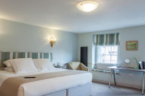 a bedroom with a bed and a desk and a window at The Salutation Inn in Topsham