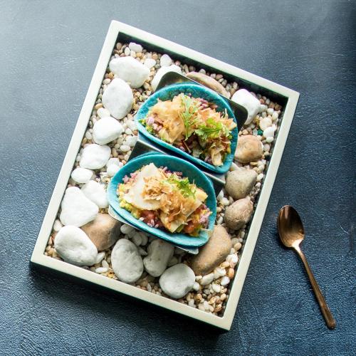 a tray with three dishes on rocks and a spoon at The Reverie Saigon Residential Suites in Ho Chi Minh City
