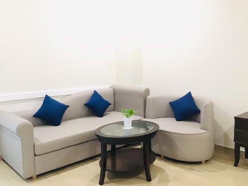 a living room with a couch with blue pillows and a table at Quê Tôi Hotel in Soc Trang