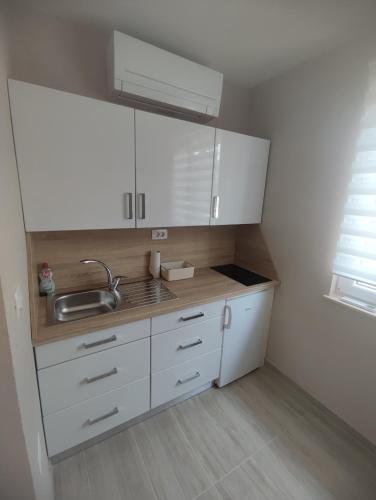 a small kitchen with white cabinets and a sink at Lavanda & limone in Koper